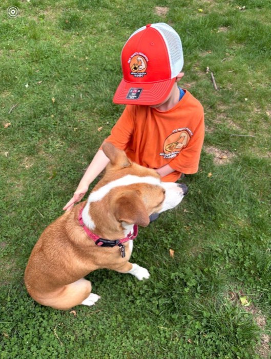 One of Mark's boys in a Heavy Doody Scoops hat petting Lissy in the grass